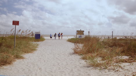 people walking to and from folly beach entrance, day, dolly in