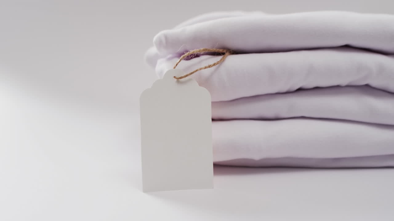 Video of stack of folded white t shirts with copy space on white background