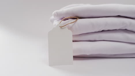 video of stack of folded white t shirts with copy space on white background