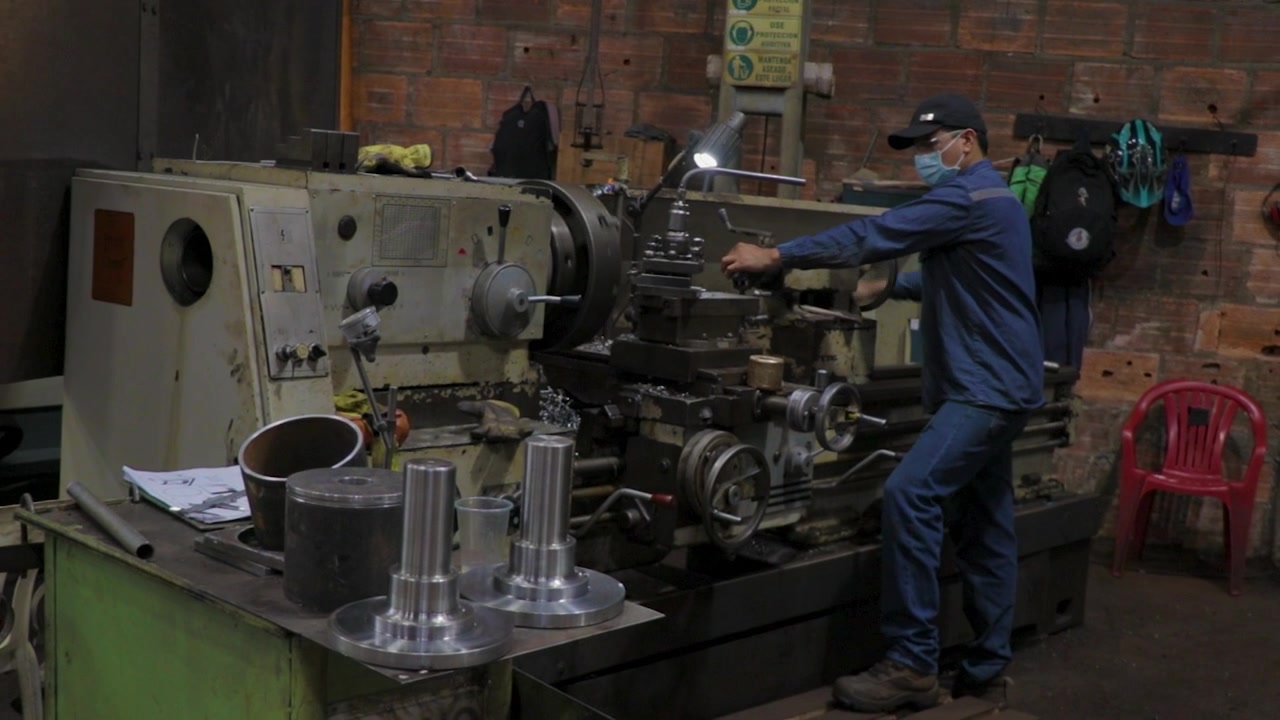 Operaio che aziona una macchina automatica nell'industria metallurgica.