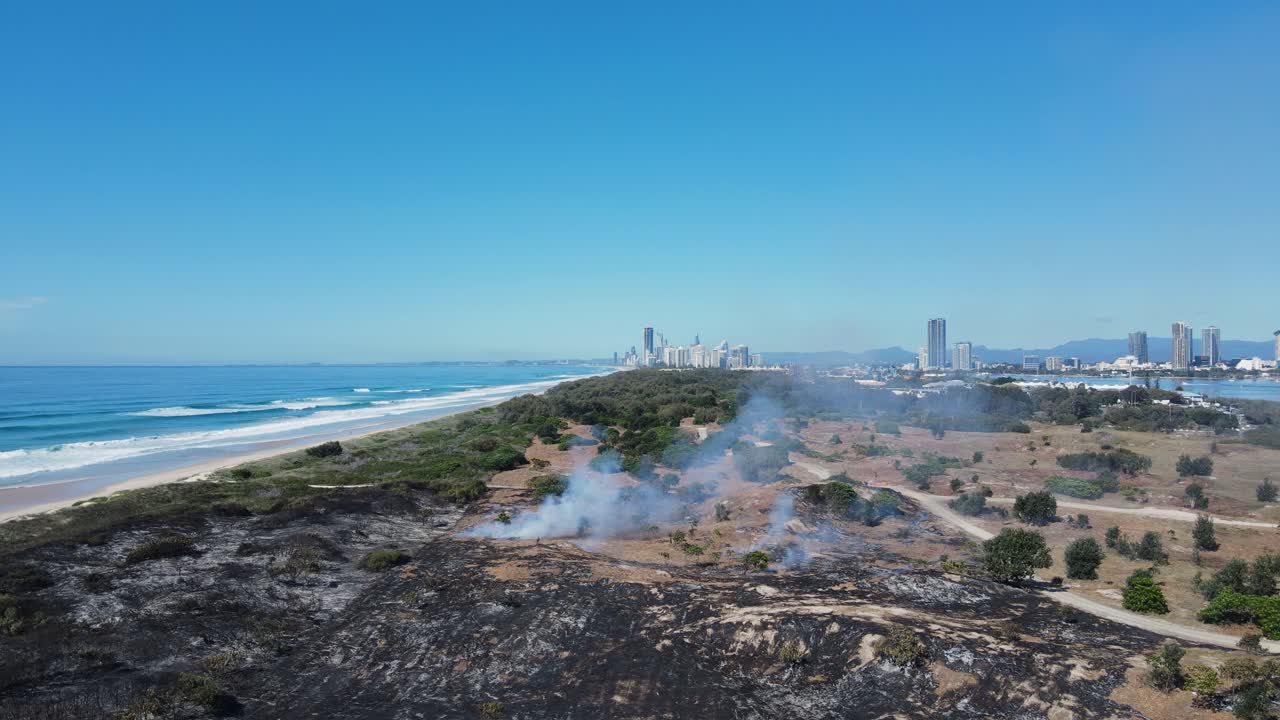 산불로 인해 모래 언덕 위로 연기가 피어오르는 해안 도시 스카이라인의 전망