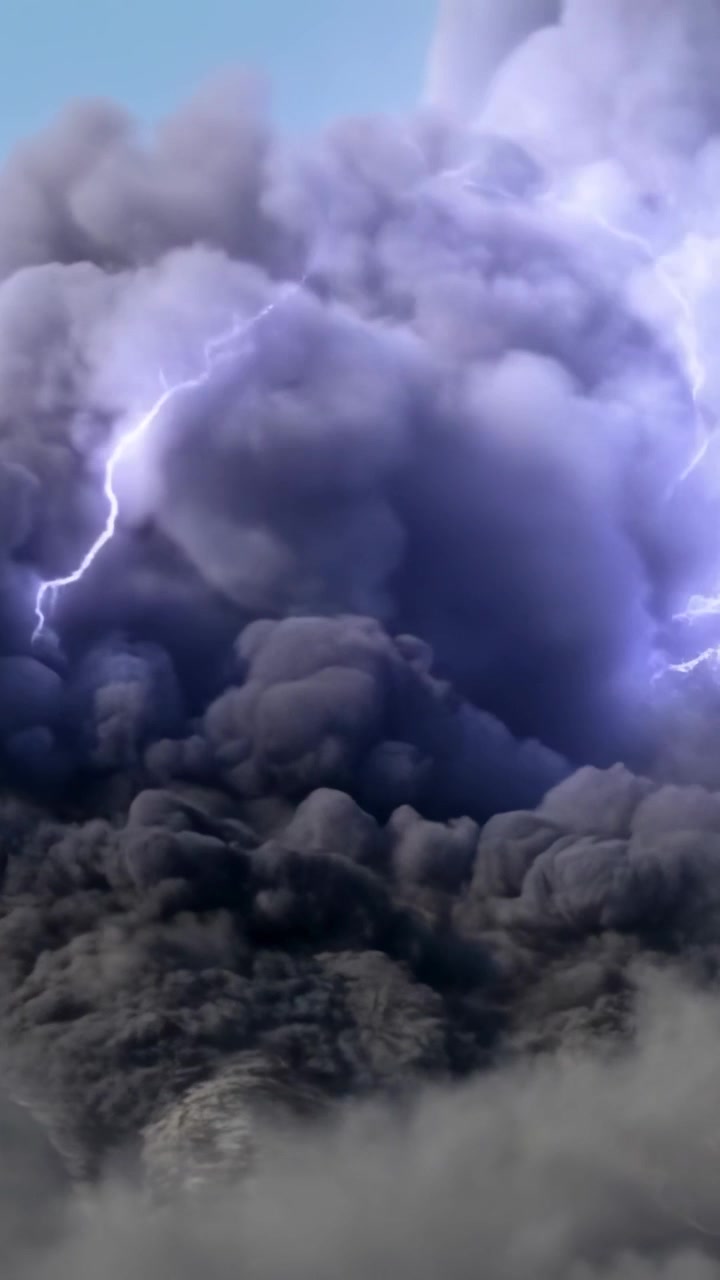 Video verticale: Fulmine ramificato che colpisce un pennacchio di fumo carico sotto un cielo blu, illuminando una foschia di cenere.