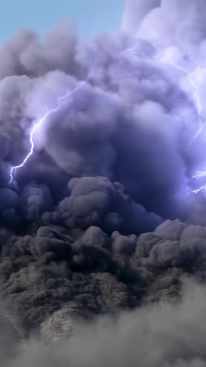 Video verticale: Fulmine ramificato che colpisce un pennacchio di fumo carico sotto un cielo blu, illuminando una foschia di cenere.