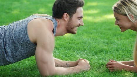 Happy-couple-training-plank-exercise-in-summer-park.-Sport-couple-concept