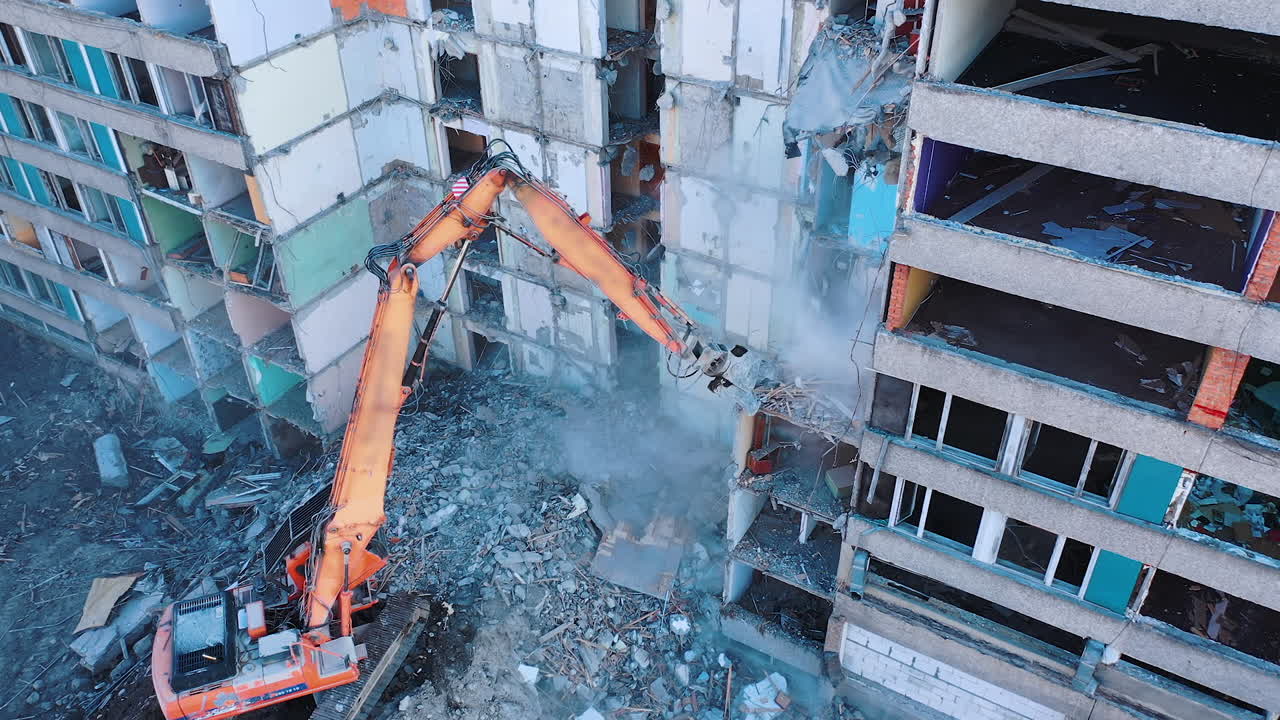 Dismantling of a high bulding. Excavator demolishing ruins for new construction project. Flying above a destruction.