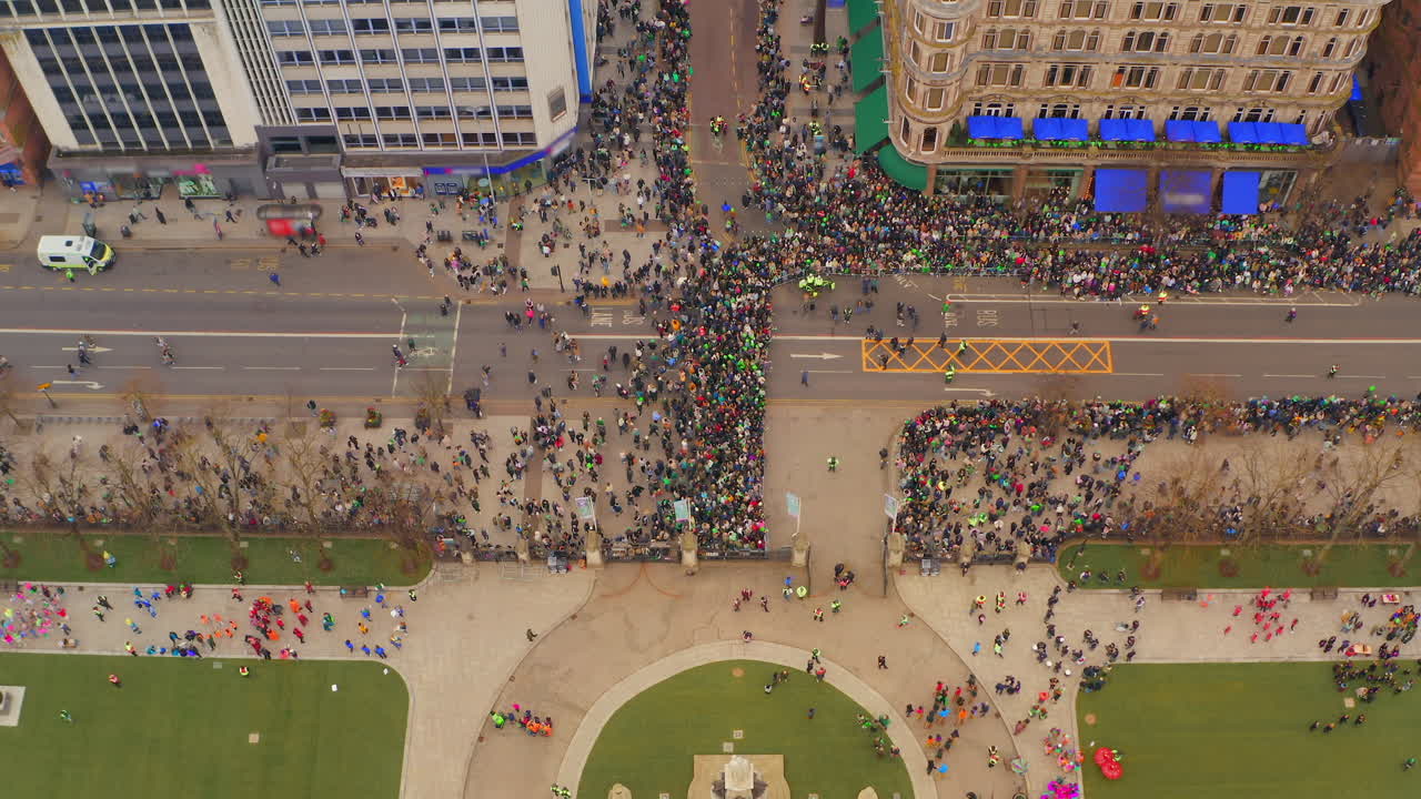 Aerial ascent reveals Paddy's Day preparations and gathering crowds at historic City Hall