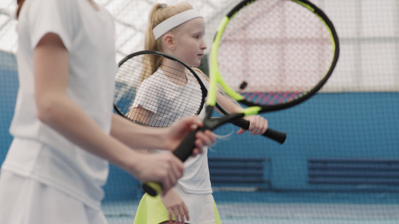 Little Girls Practicing Tennis On Court