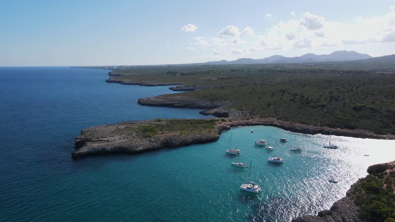 Witness the breathtaking beauty of Cala Varques in Porto Cristo, Majorca. Enjoy azure waters, rocky coastlines, and serene boats anchored in a picturesque cove. A perfect escape to nature’s splendor.