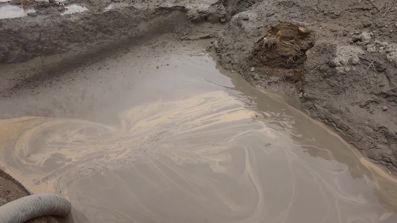 Acqua fangosa che riempie un fosso in un campo agricolo