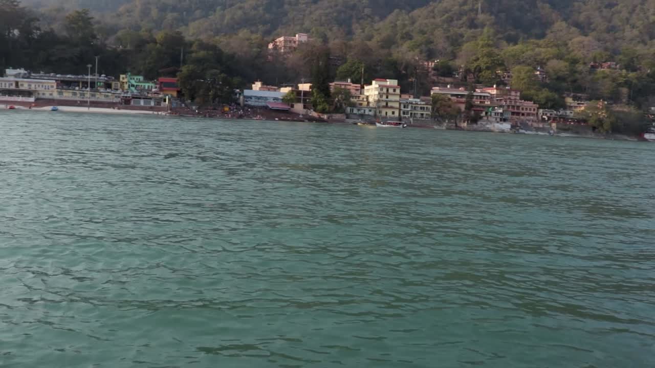 una joven india aislada sentada en la orilla del río ganges desde un ángulo diferente