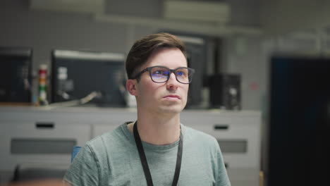 person working at computer, focused on multiple monitors in modern office environment, wearing glasses, managing system or network tasks, tech workspace, computer setup with multiple screens