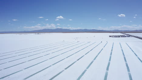 Forward-aerial-of-people-by-rows-of-water-at-salt-flats-in-Argentina