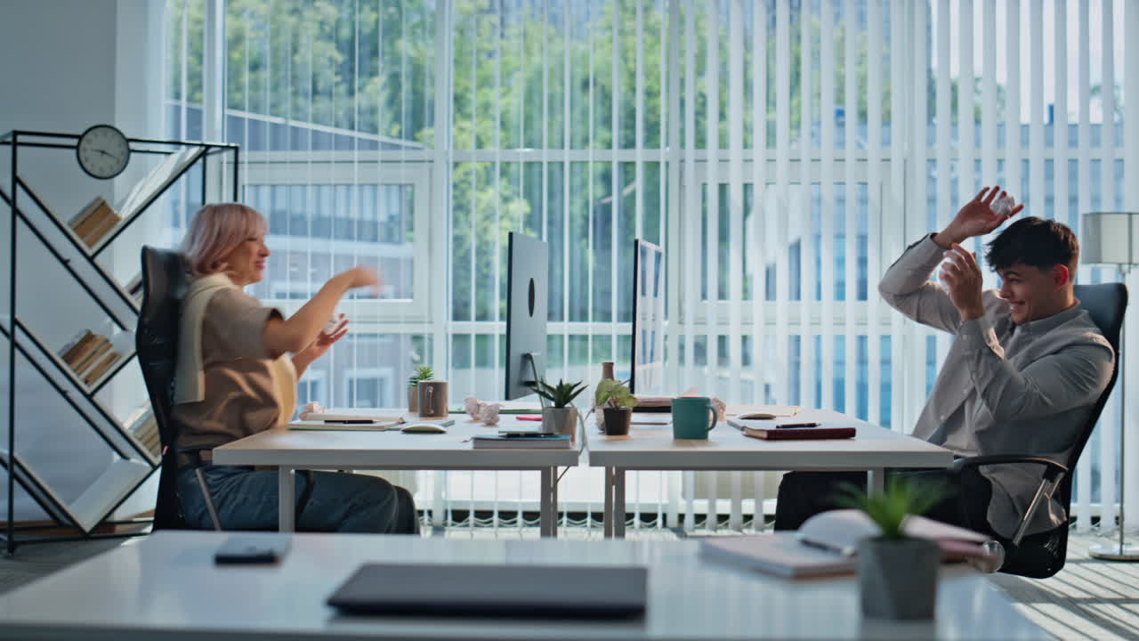 Carefree coworkers having fun at light office. Happy woman man fooling around