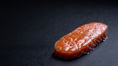 salmón en rebanadas sobre un fondo de piedra oscura
