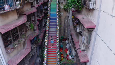Vista-Aérea-De-Una-Mujer-Caminando-Por-Las-Empinadas-Escaleras-Pintadas-En-Chongqing,-China