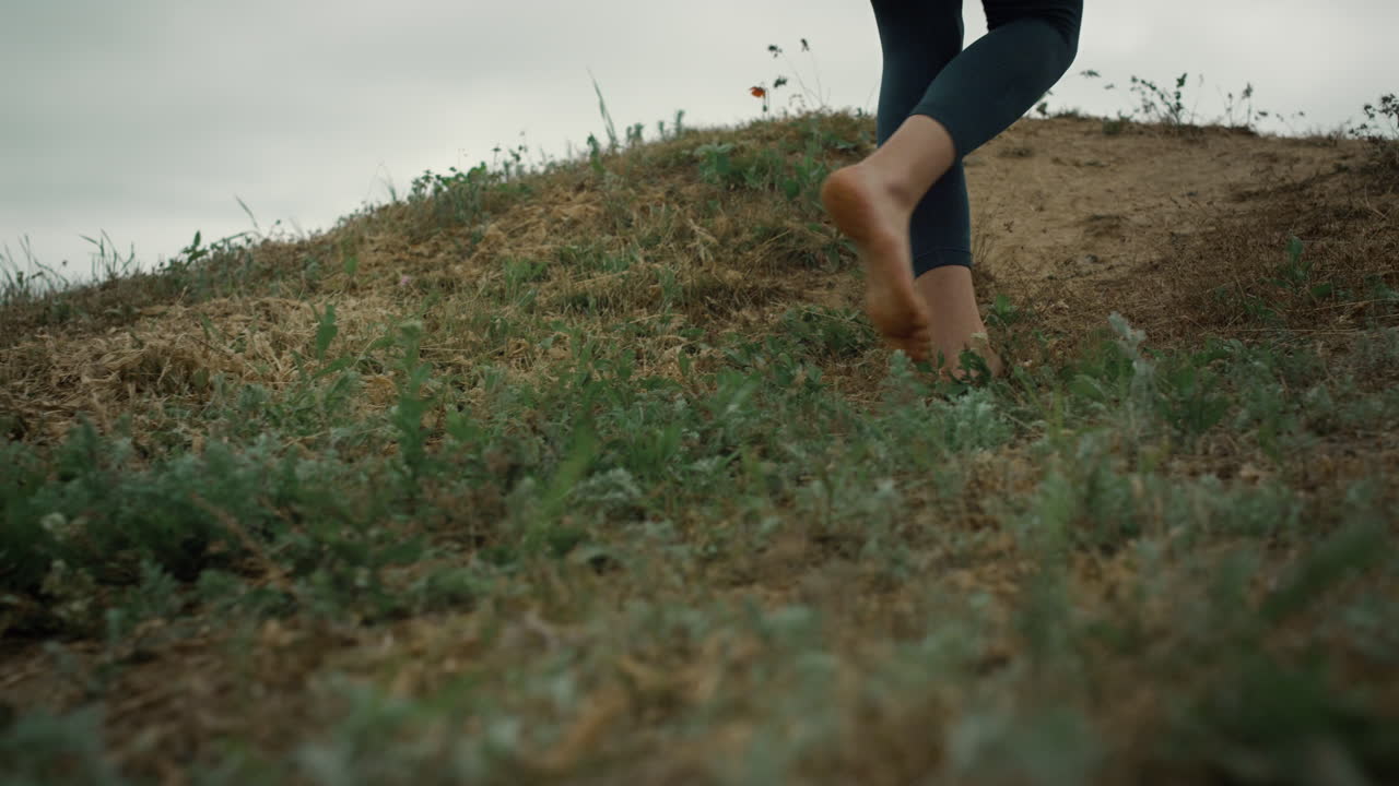 Athletic woman legs walking up hill close up. Unknown sporty girl climb hilltop.