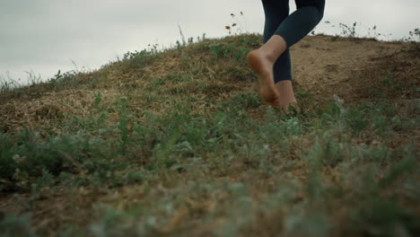 Athletic-woman-legs-walking-up-hill-close-up.-Unknown-sporty-girl-climb-hilltop.