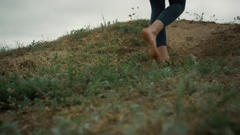 athletic woman legs walking up hill close up. unknown sporty girl climb hilltop.