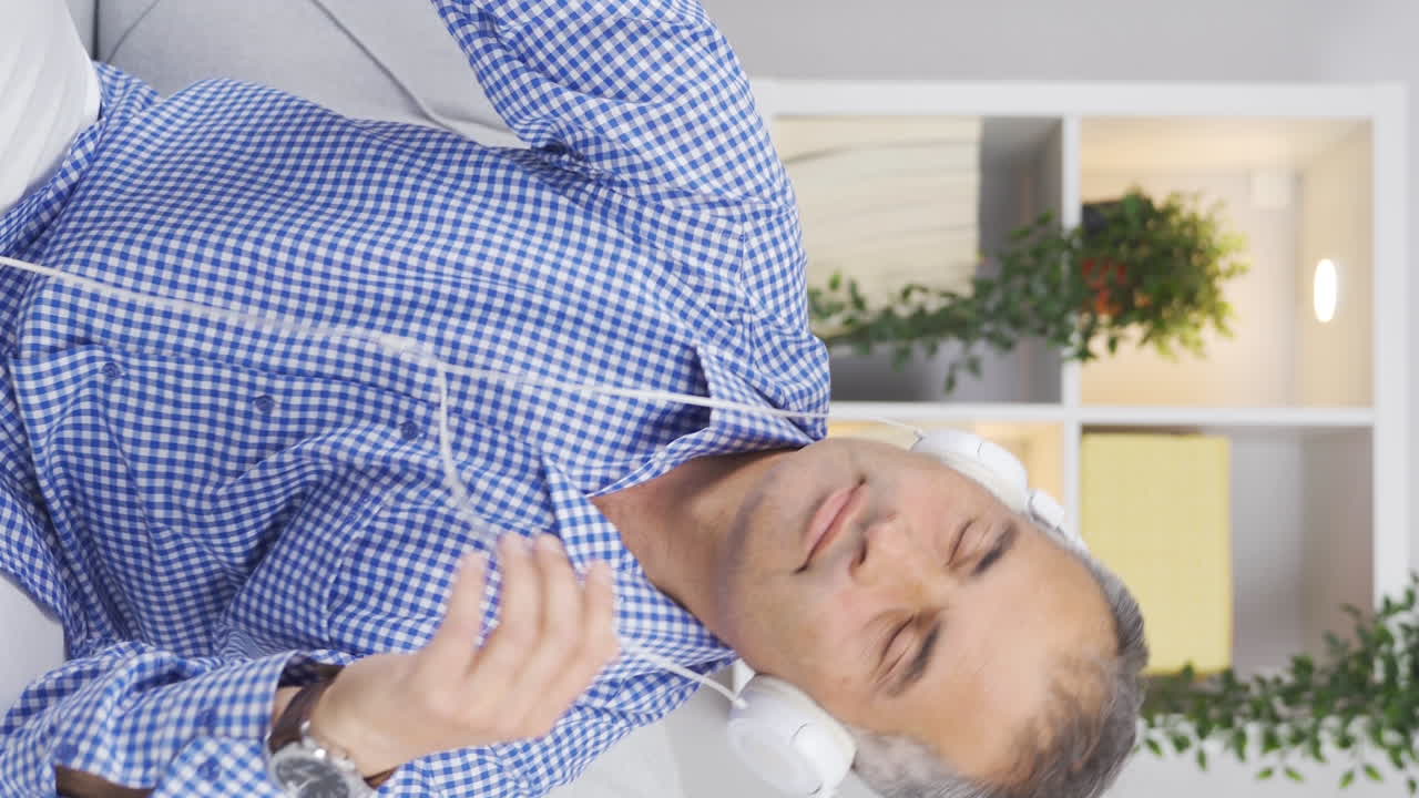 el video vertical de un hombre escuchando música con auriculares es infeliz y triste.