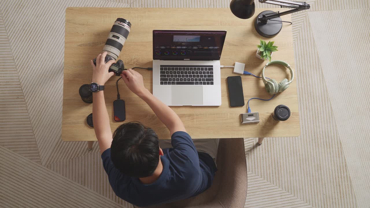Top View Of A Male Color Grading Putting The Memory Card On A Laptop Then Choosing The Video In The Workspace At Home