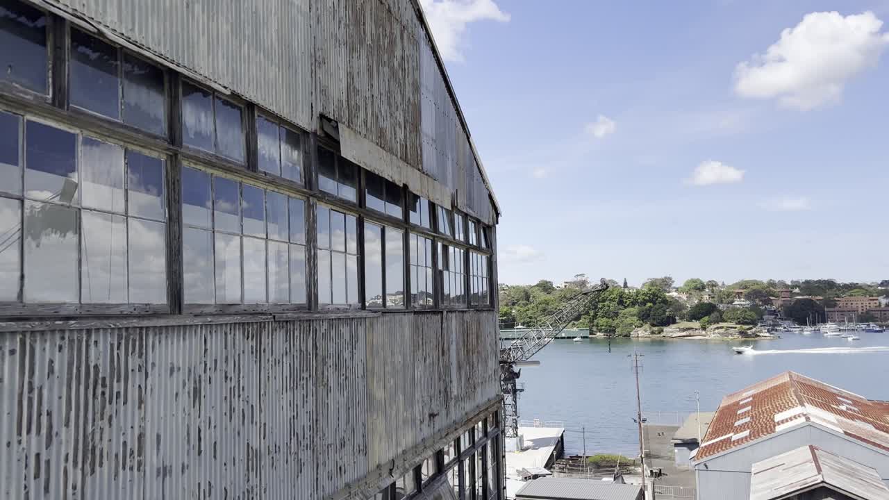 An old warehouse in the foreground as a boat passes by on the historical industrial Cockatoo Island in Sydney harbour, Australia