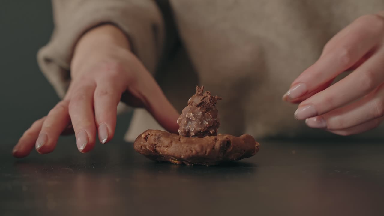 İç mekanda bir masada, kremalı soslu çikolatalı hamur işini tabağa yerleştiren eller.