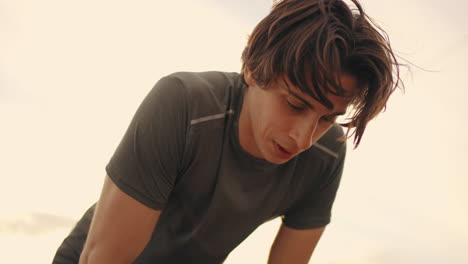 exhausted-young-male-athlete-after-jog-or-training-outdoors-portrait-of-man-against-sky