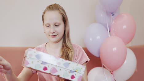 el niño abre una caja con un regalo de cumpleaños.