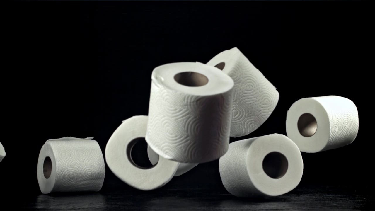 White Toilet Paper Rolls Falling in Slow Motion on Black Background