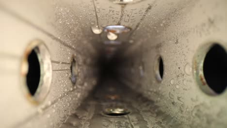 pushing into a wet zinc-plated steel perforated square tube with a wide angle macro probe lens - as a red laser light moves on the bottom of the tube, in the middle of the tube and the clip