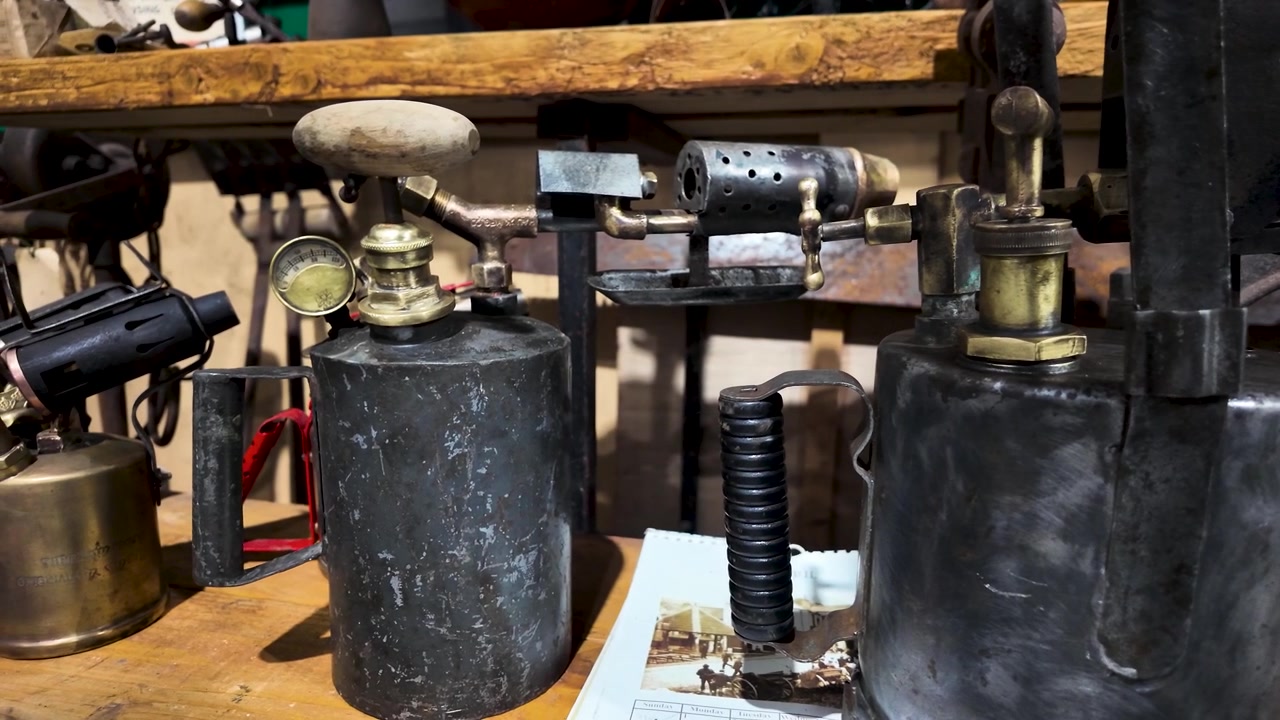 Detailed close-up of vintage blow torches on a rustic workbench, showcasing their industrial design and historical heritage.