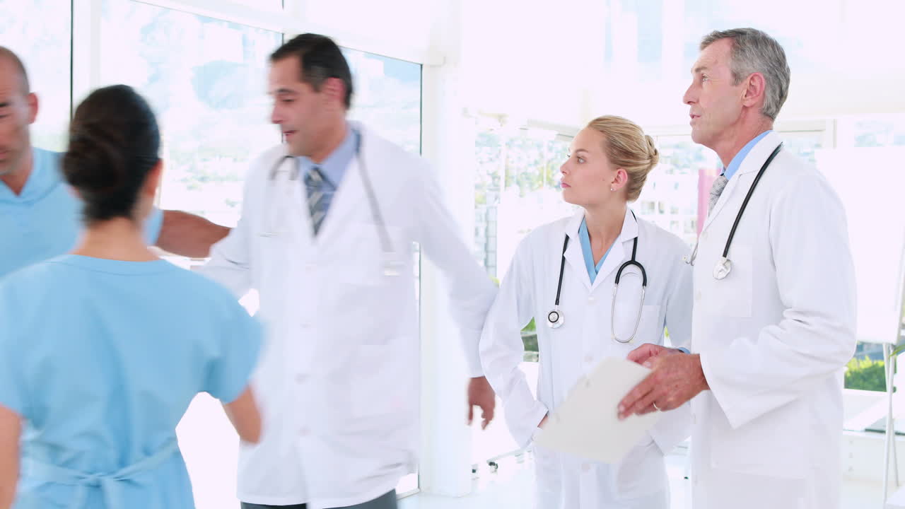 의사들은 클립보드를 보고 있고, 그 중 한 명은 외과 의사와 함께 있습니다.