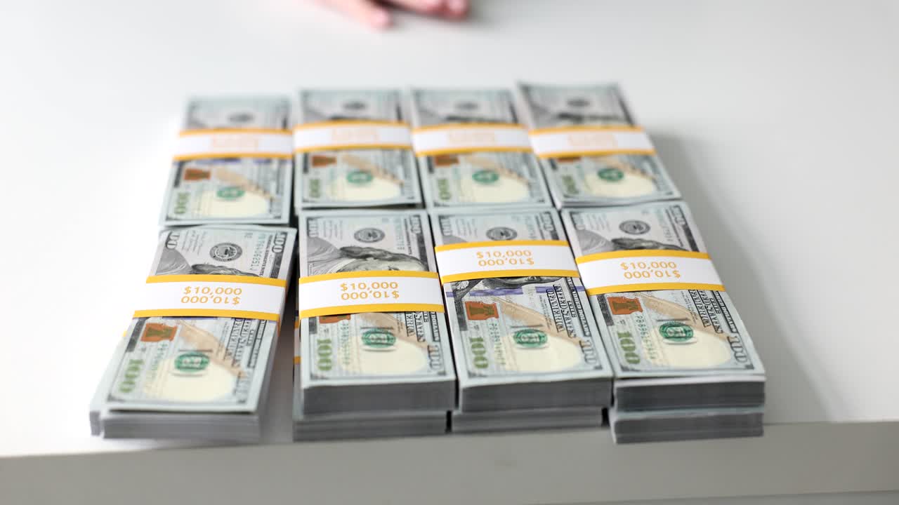 Woman moves away stacks of dollar banknotes on white table