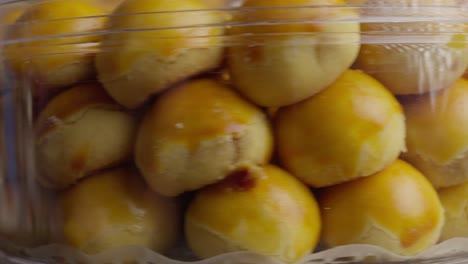 clear round container with delicious crumbly round filled pastry, nastar an indonesian pineapple filled tart