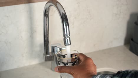 close-up of a faucet pouring water into a glass