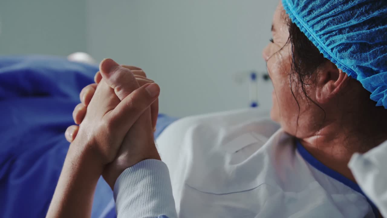 primer plano de un hombre reconfortando a una mujer embarazada durante el parto en el teatro de operaciones en el hospital