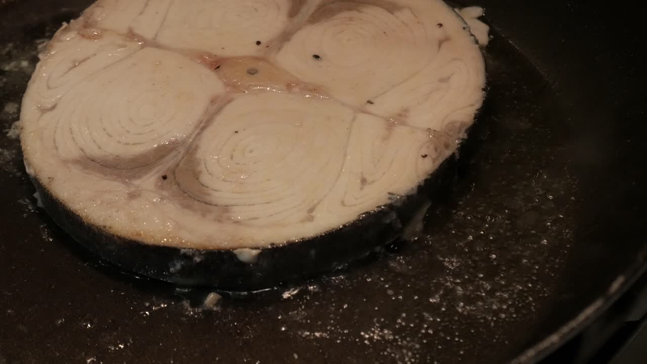 Cooking swordfish steak sizzles in a pan, fresh and appetizing view