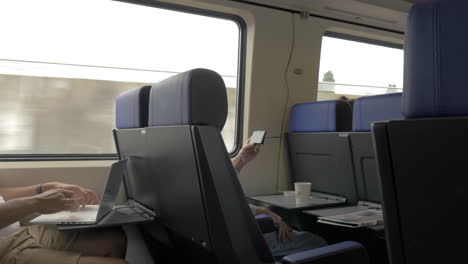 men using cellphone and laptop in commuter train