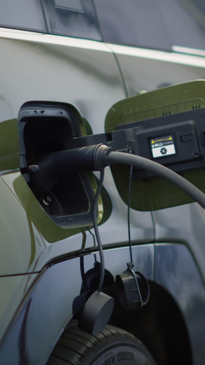 Dikey video. Modern bir istasyonda şarj olan elektrikli SUV otomobilin yakın çekim görüntüsü