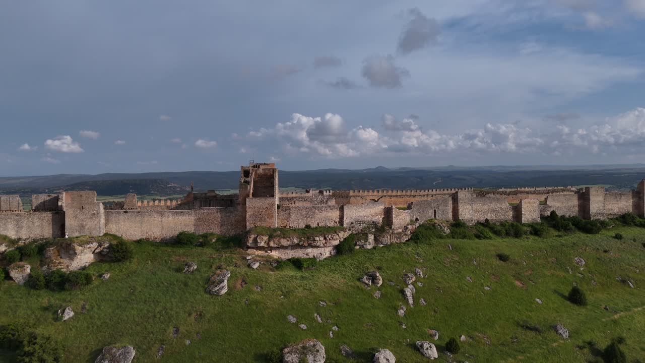 An aerial drone view of the impossing and vast Gormaz fortess, recorded at the golden hour under a blue sky with few clouds.