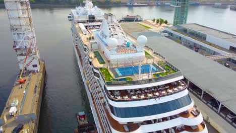 regent seven seas grandeur cruise ship lit up against skyline, docked and glowing on the water at sunset, aerial orbit
