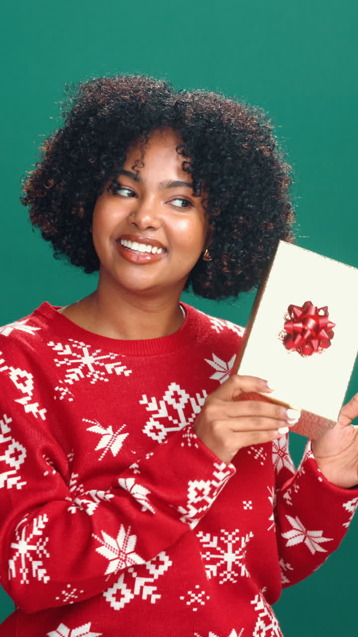 Jovem feliz segurando um presente de Natal em um plano de fundo verde