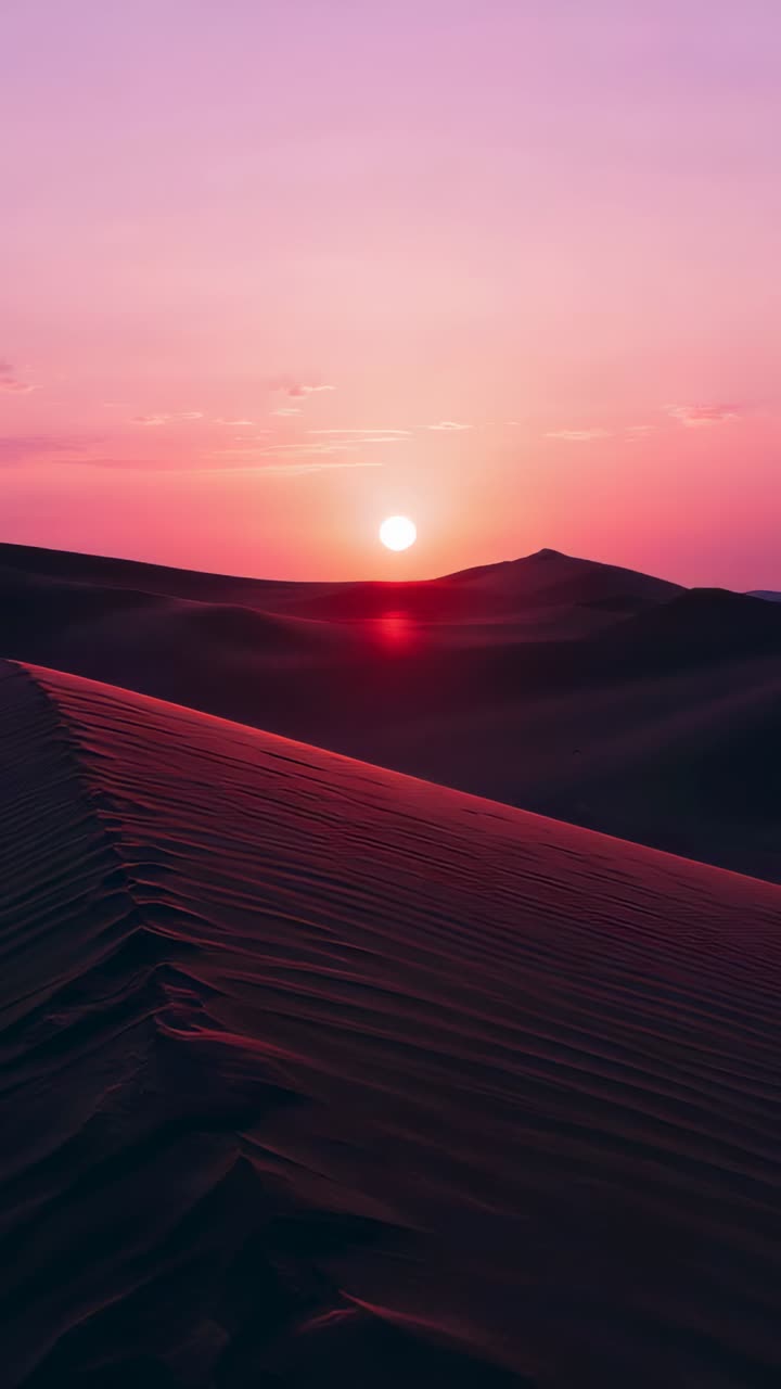 Vertical video: Approaching sun moving to horizon in desert, lighting red flash on dune ridge