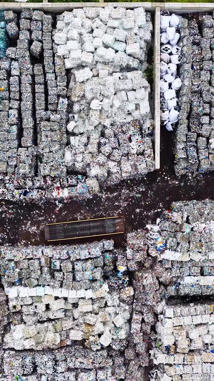 Aerial top backdrop of compacted recyclable materials stacked in organized bundles at recycling yard, drone overview