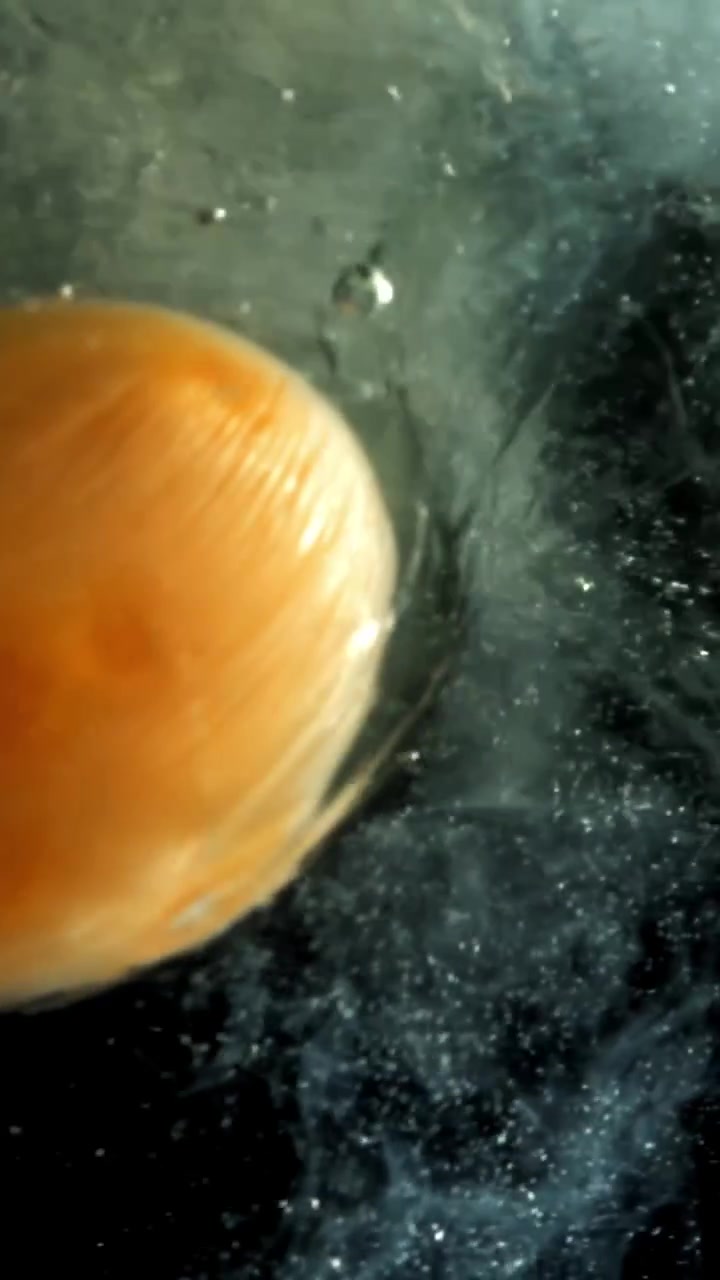 Egg Yolk and White Spreading in Water on Black Background