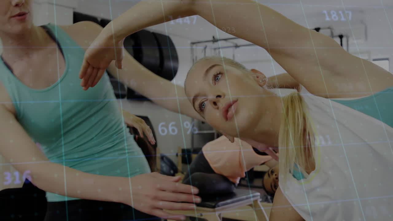 Group performing Pilates side stretches in fitness studio, showing animated muscle charts and icons
