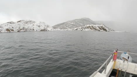 white-tailed eagle, also known as a sea eagle, soaring then diving down to catch fish on a foggy overcast day out on the ocean in front of beautiful snow capped mountains