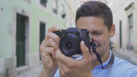 fotografo maschio sorridente con una fotocamera digitale all'aperto.