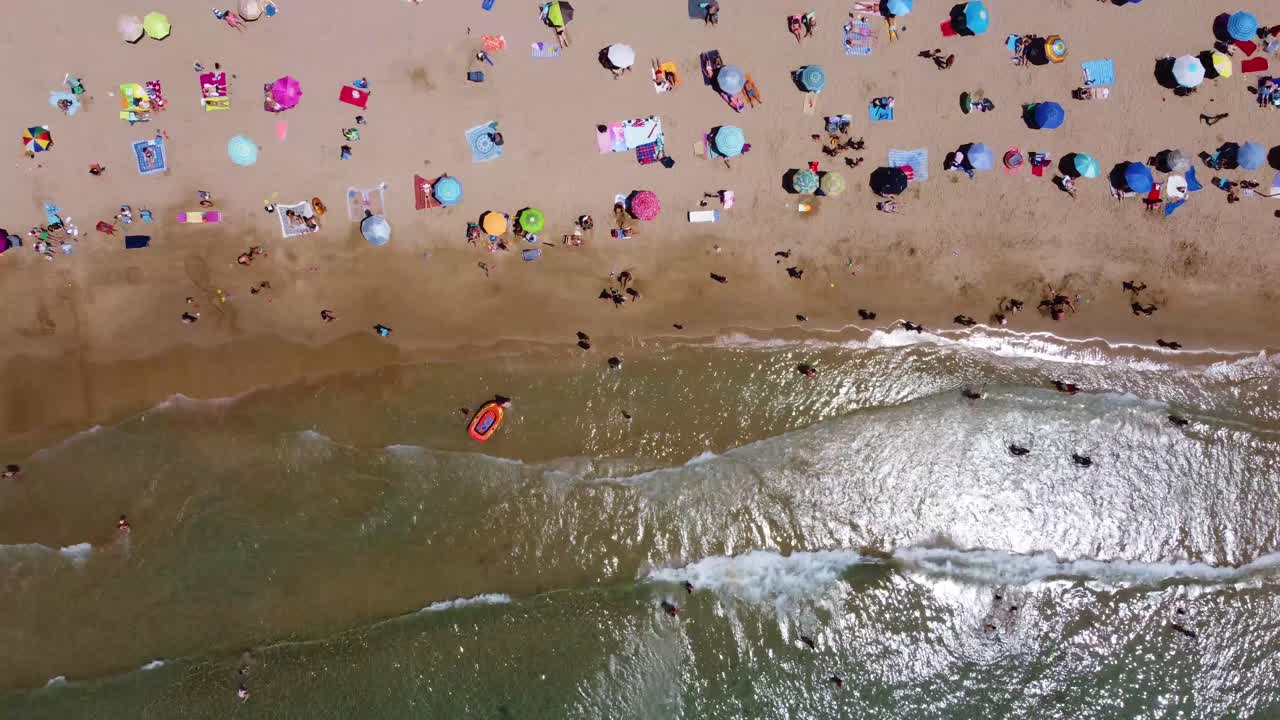 vista de pájaro del colorido paraguas turístico en la playa con olas marinas