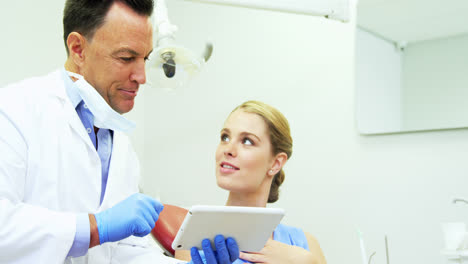 dentist discussing over digital tablet with female patient